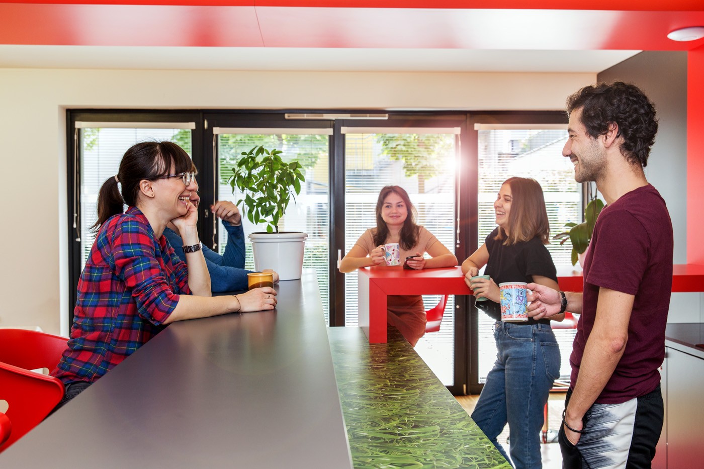 H7_Gemeinschaftsraum_2 Gruppe junger Studenten sitzen und stehen an Küchenbar in Gemeinschaftsküche und unterhalten sich