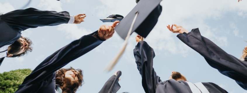 Graduated students celebrate their achievements in a park, reminiscing on beautiful university memories and congratulating each other.